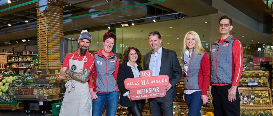 Geschäftsleiterin Birgit Köpf in der Mitte links, Regionaldirektor Andreas Mark in der Mitte rechts und die Mitarbeitenden im Interspar-Hypermarkt in Bürs freuen sich über die Eröffnung im März 2024.  