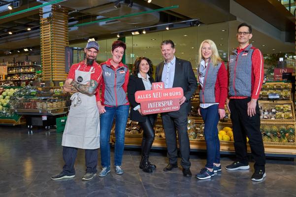 Geschäftsleiterin Birgit Köpf in der Mitte links, Regionaldirektor Andreas Mark in der Mitte rechts und die Mitarbeitenden im Interspar-Hypermarkt in Bürs freuen sich über die Eröffnung im März 2024.  