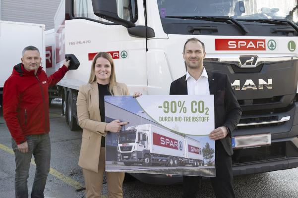 Die Spar-Zentrale stellte die gesamte Lkw-Flotte auf HVO-Diesel um. Der biobasierte Treibstoff wird aus Altspeisefetten gewonnen und spart bis zu 90% der Treibhausgas-Emissionen im Vergleich zu fossilem Diesel ein. Spar-Geschäftsführerin Patricia Sepetavc, Logistikleiter Florian Peer und Spar-Kraftfahrer Zeljko Gavric freuen sich über die Einsparung von CO2.  
